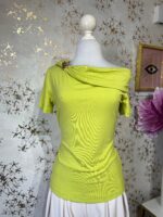 Blusa asimétrica verde lima, con broche dorado en una manga