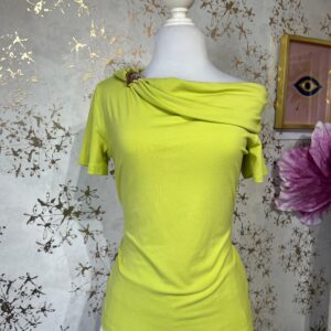 Blusa asimétrica verde lima, con broche dorado en una manga