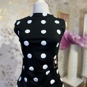 Blusa negra de lunares blancos con broche dorado en la cintura